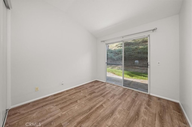 empty room with vaulted ceiling, baseboards, and wood finished floors