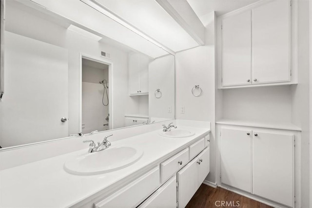 full bathroom with a sink, a shower, wood finished floors, and double vanity