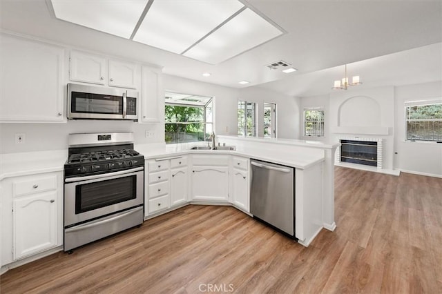 kitchen featuring appliances with stainless steel finishes, white cabinetry, a peninsula, and a sink