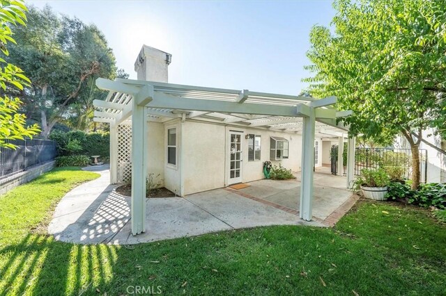 rear view of property featuring stucco siding, a pergola, a patio, fence, and a chimney