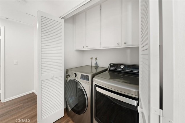 clothes washing area with cabinets, washing machine and dryer, and hardwood / wood-style floors