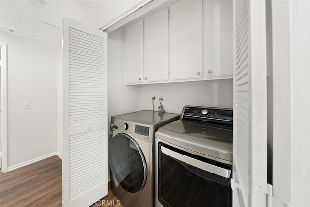 laundry room featuring cabinet space, washer and dryer, light wood-type flooring, and baseboards