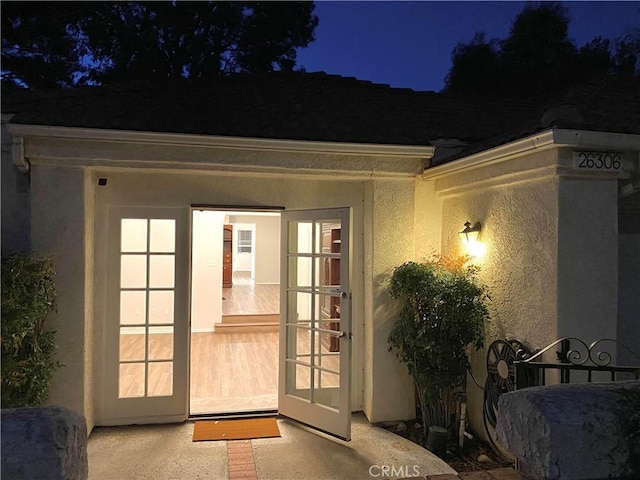 exterior entry at night featuring stucco siding