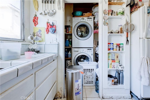 clothes washing area featuring light tile patterned flooring and stacked washing maching and dryer