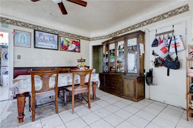 dining space featuring light tile patterned floors, ceiling fan, stacked washer and dryer, and a textured ceiling