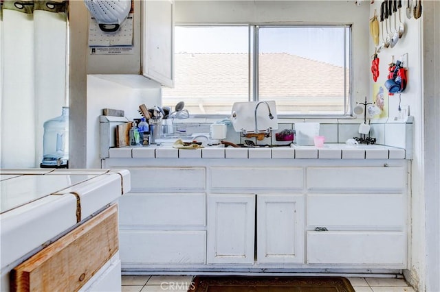 kitchen featuring white cabinets, light tile patterned floors, and tile countertops