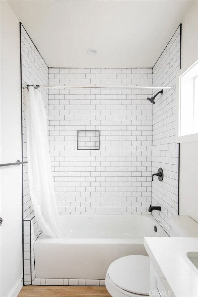 full bathroom featuring hardwood / wood-style floors, vanity, toilet, and shower / tub combo