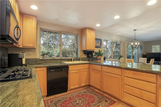 kitchen featuring light wood-type flooring, black appliances, dark stone countertops, sink, and a chandelier