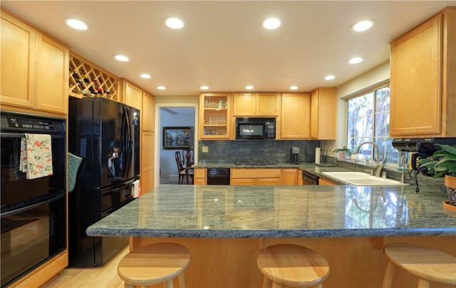 kitchen with sink, a breakfast bar area, kitchen peninsula, and black appliances