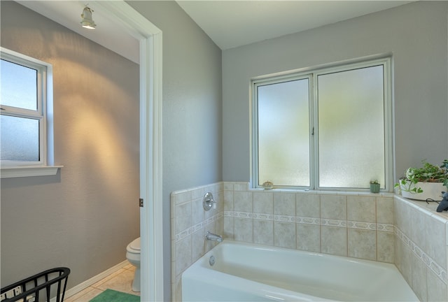 bathroom with a bathtub, a healthy amount of sunlight, tile patterned flooring, and toilet