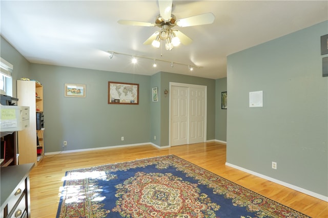 unfurnished living room with rail lighting, light hardwood / wood-style flooring, and ceiling fan