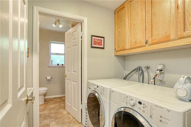 washroom with cabinets, washing machine and dryer, and light tile patterned flooring