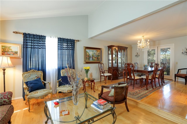 living room with french doors, light hardwood / wood-style flooring, a chandelier, and vaulted ceiling