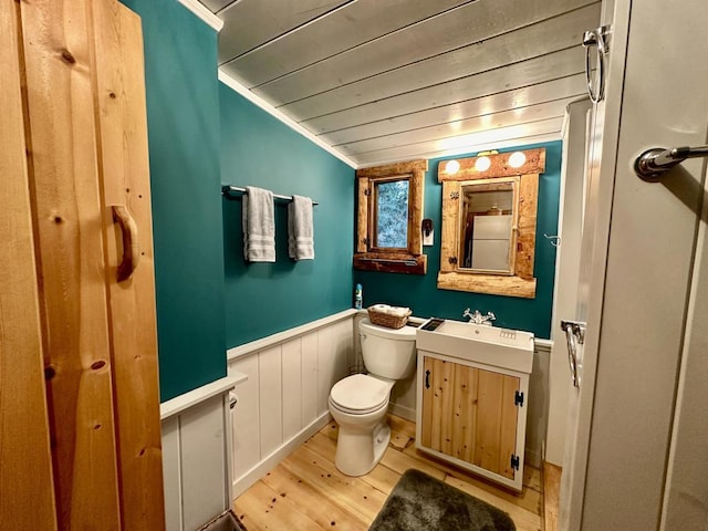 bathroom featuring toilet, wood-type flooring, vaulted ceiling, ornamental molding, and vanity