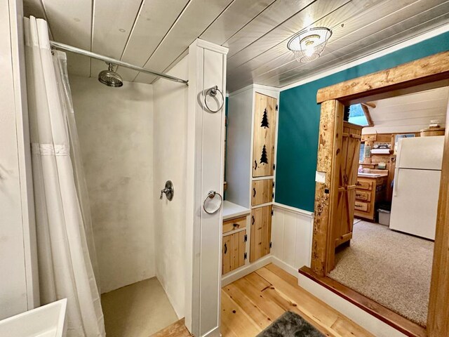 bathroom with hardwood / wood-style flooring, wood walls, and a shower with shower curtain