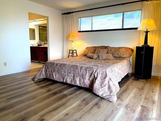 bedroom with hardwood / wood-style flooring, ensuite bath, and a textured ceiling