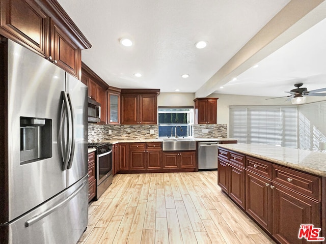 kitchen featuring ceiling fan, sink, backsplash, appliances with stainless steel finishes, and light hardwood / wood-style floors