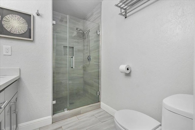 bathroom featuring vanity, a shower with shower door, and toilet