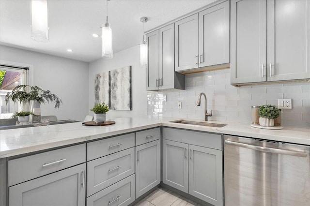 kitchen featuring sink, gray cabinetry, light stone counters, decorative light fixtures, and stainless steel dishwasher