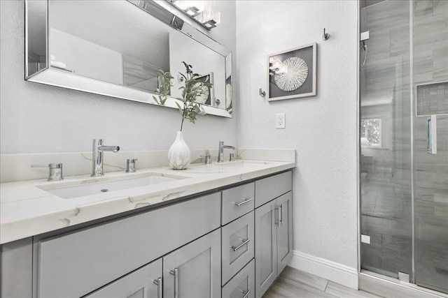 bathroom featuring a shower with door and vanity