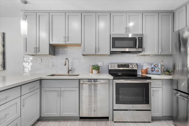 kitchen featuring gray cabinets, sink, backsplash, hanging light fixtures, and stainless steel appliances