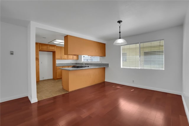 kitchen featuring pendant lighting, kitchen peninsula, and light hardwood / wood-style flooring