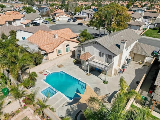 exterior space featuring a fenced backyard, a residential view, a pool with connected hot tub, and a patio