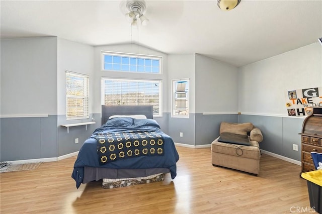 bedroom featuring lofted ceiling, a wainscoted wall, and wood finished floors