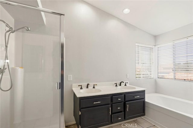 full bathroom featuring a garden tub, double vanity, a stall shower, and a sink