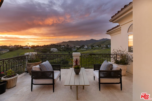 balcony at dusk featuring a mountain view and outdoor lounge area