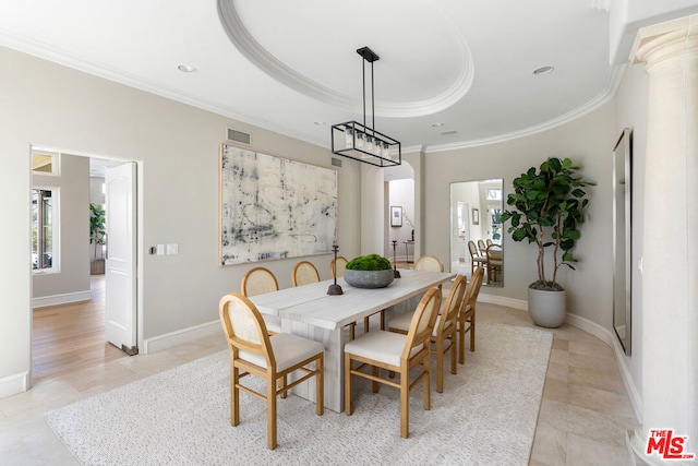 dining space with ornate columns, ornamental molding, and a tray ceiling