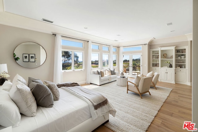 bedroom with multiple windows, access to exterior, light hardwood / wood-style floors, and french doors