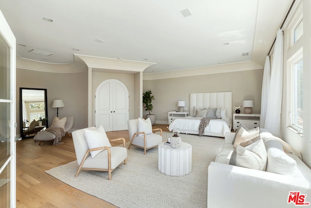 bedroom featuring multiple windows, light hardwood / wood-style flooring, and ornamental molding