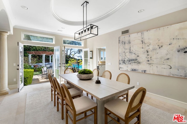 tiled dining space with ornamental molding, a tray ceiling, and decorative columns