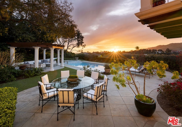 patio terrace at dusk with outdoor lounge area and a pergola