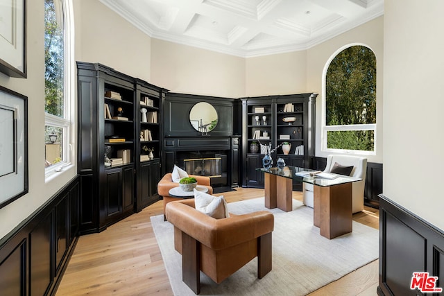 office space with beamed ceiling, a high ceiling, ornamental molding, coffered ceiling, and light hardwood / wood-style flooring