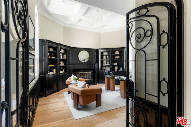 living room featuring beamed ceiling, a high ceiling, ornamental molding, coffered ceiling, and light hardwood / wood-style flooring