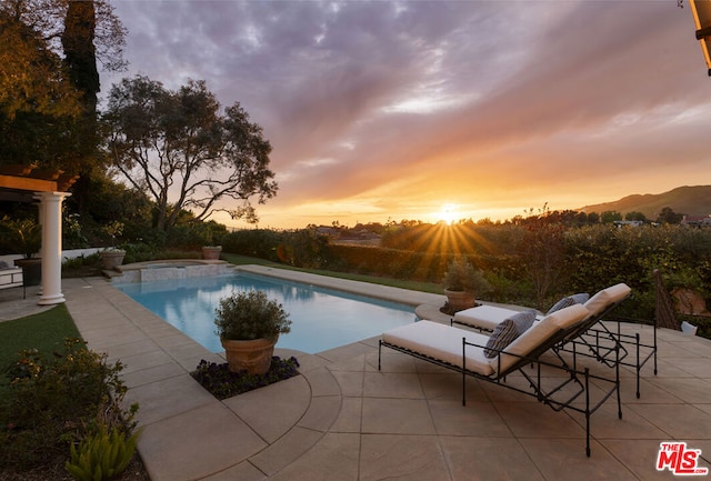 pool at dusk with a patio area