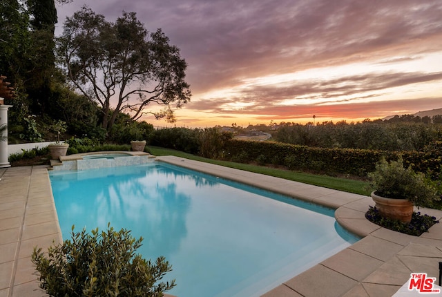 pool at dusk featuring an in ground hot tub