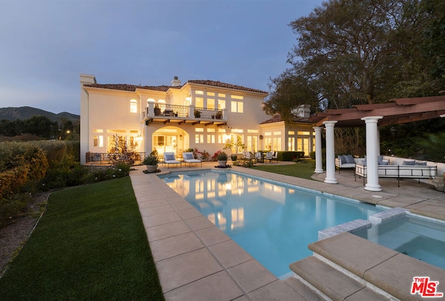 pool at dusk featuring a pergola, outdoor lounge area, a patio, a mountain view, and an in ground hot tub