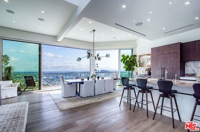 kitchen featuring a breakfast bar, an inviting chandelier, dark brown cabinets, decorative light fixtures, and hardwood / wood-style floors