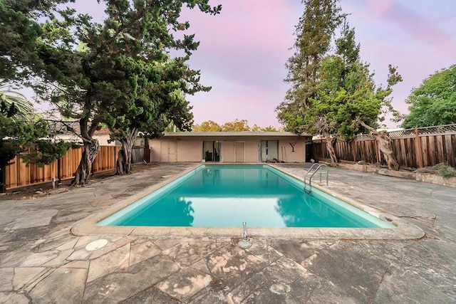 pool at dusk featuring a patio area