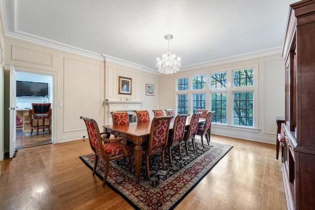 dining room with a notable chandelier, crown molding, and light hardwood / wood-style flooring