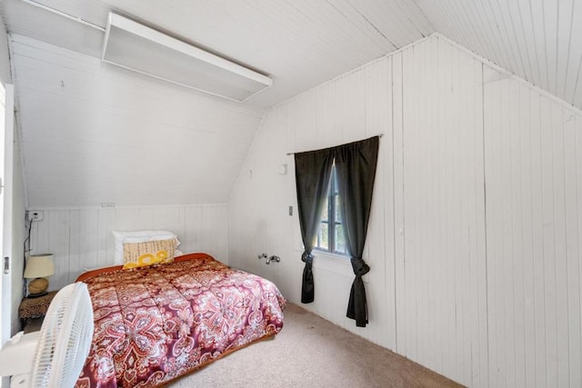 carpeted bedroom with wooden walls and vaulted ceiling