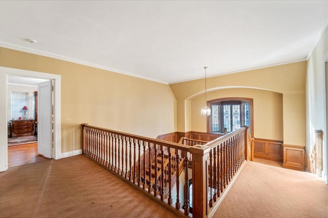 hall with ornamental molding, carpet floors, and a chandelier