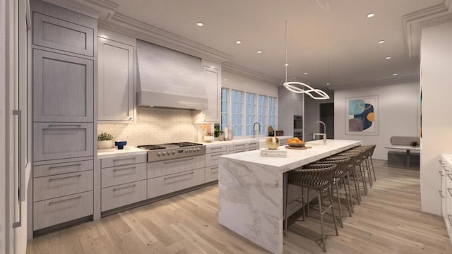 kitchen with premium range hood, light hardwood / wood-style flooring, a kitchen island with sink, and stainless steel gas stovetop