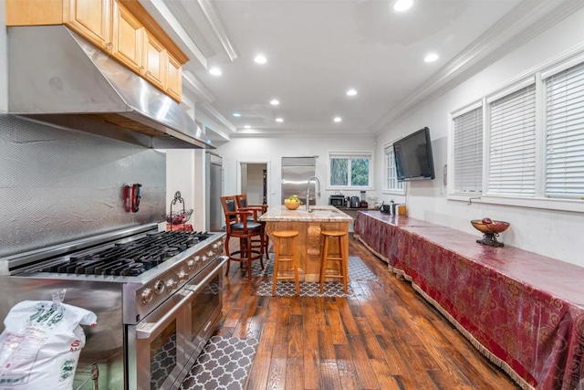 kitchen featuring a breakfast bar, a kitchen island with sink, high end stainless steel range oven, crown molding, and dark hardwood / wood-style floors