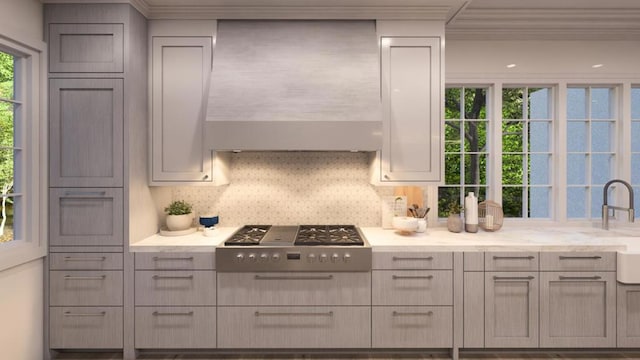 kitchen with backsplash, light stone counters, wall chimney range hood, gray cabinets, and stainless steel gas stovetop