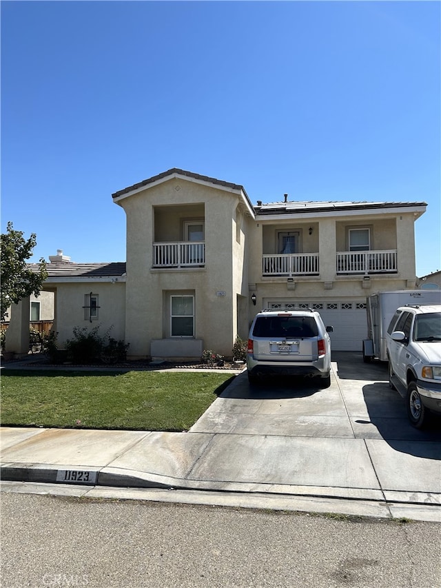 view of front of home with a front yard, a balcony, and a garage