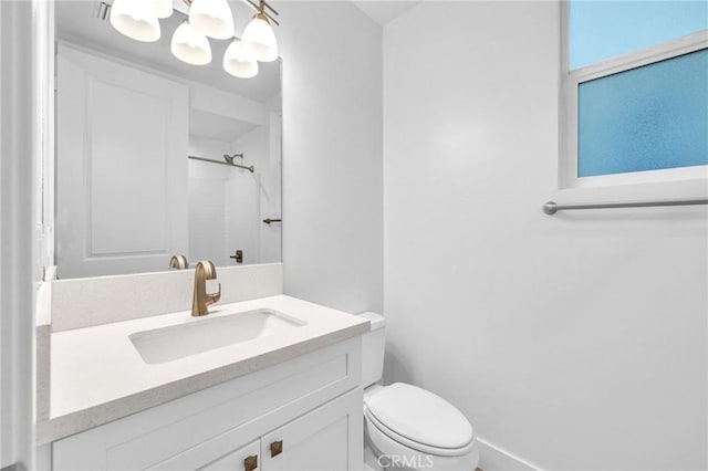 bathroom with a notable chandelier, a shower, vanity, and toilet